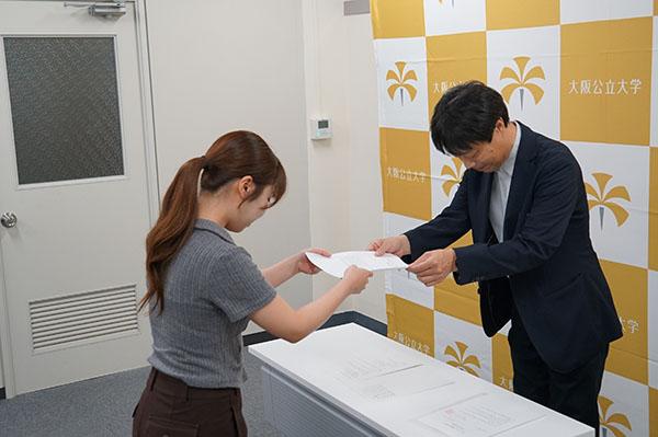 写真:通知書を渡す人と受け取る人