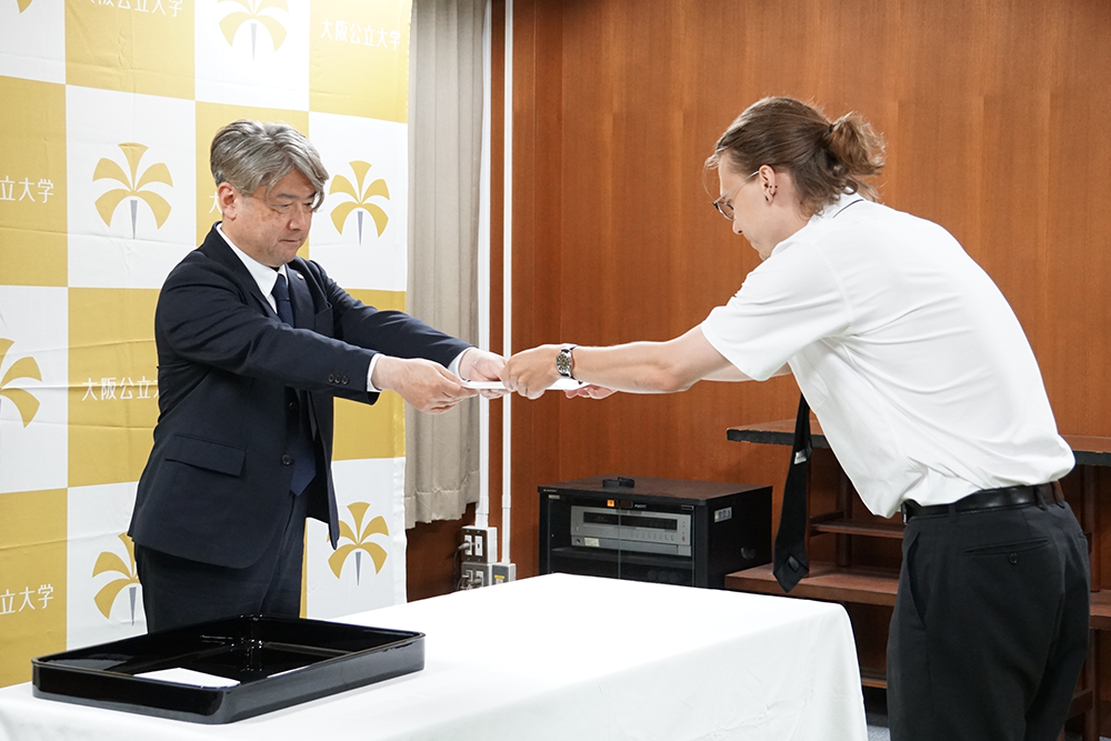 写真:通知書を渡す人と受け取る人